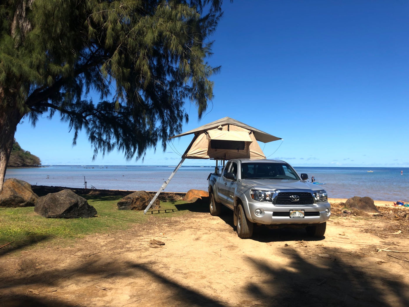 Sunny beach scene with a silver pickup truck sporting a rooftop tent, a unique type of rv rental for beach camping adventures. — photo 5
