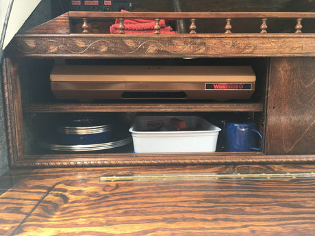 RV rental interior showing wooden storage: Winnebago appliance, blue speckled dishes, and various travel essentials.