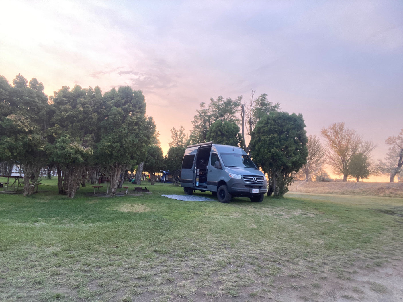 RV rental van parked at a twilight campsite, surrounded by trees. Perfect for outdoor adventures and van life.