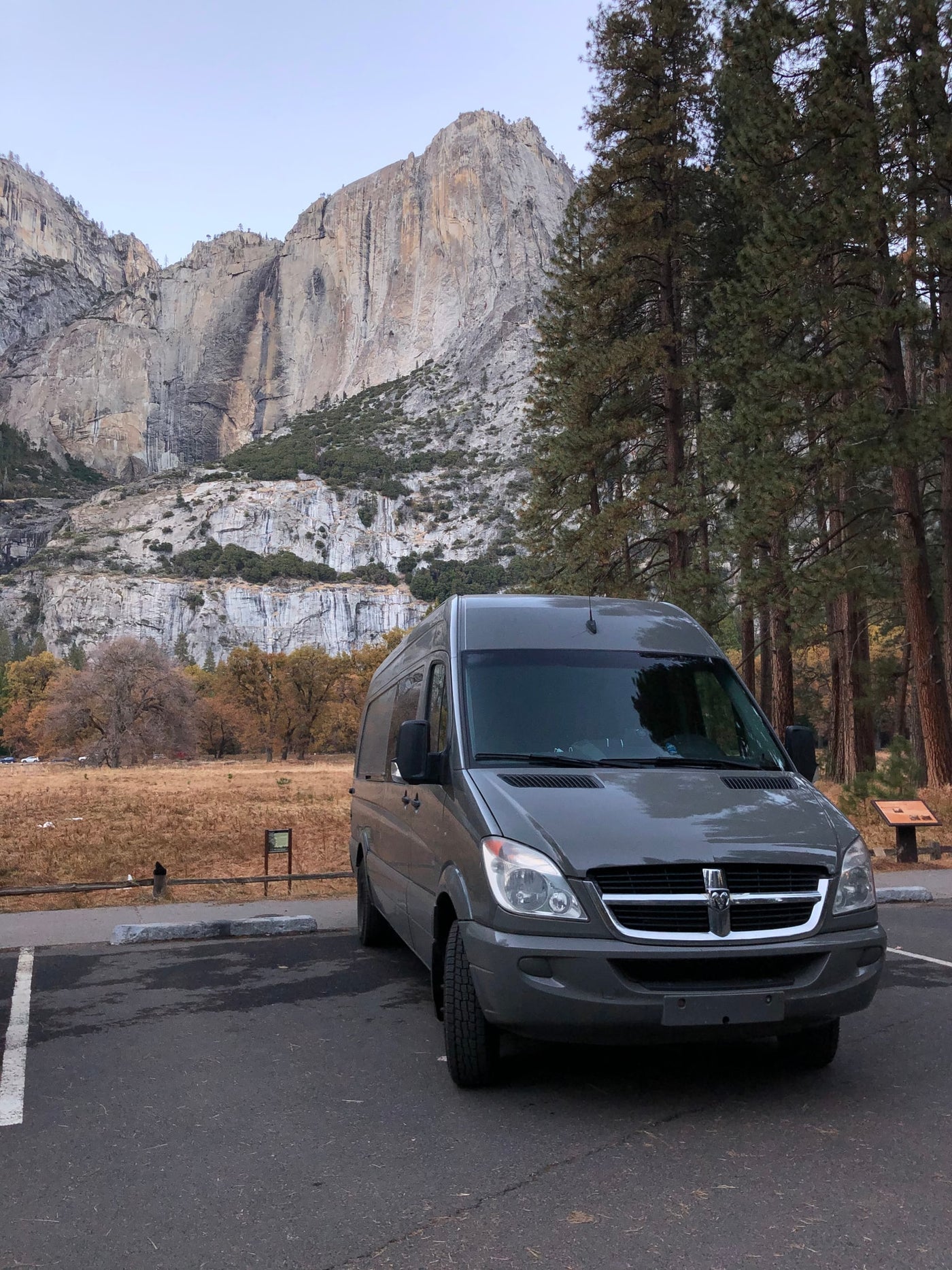 A grey rv rental van is parked in Yosemite National Park, with majestic granite cliffs and autumn-toned meadows. — photo 9