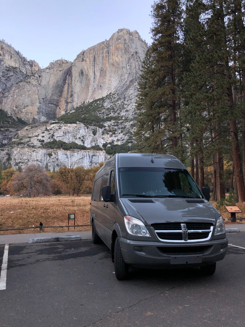 A grey rv rental van is parked in Yosemite National Park, with majestic granite cliffs and autumn-toned meadows. — photo 9