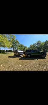 Green Bronco towing an **rv rental** (gray camper) in a sunny field for adventure.