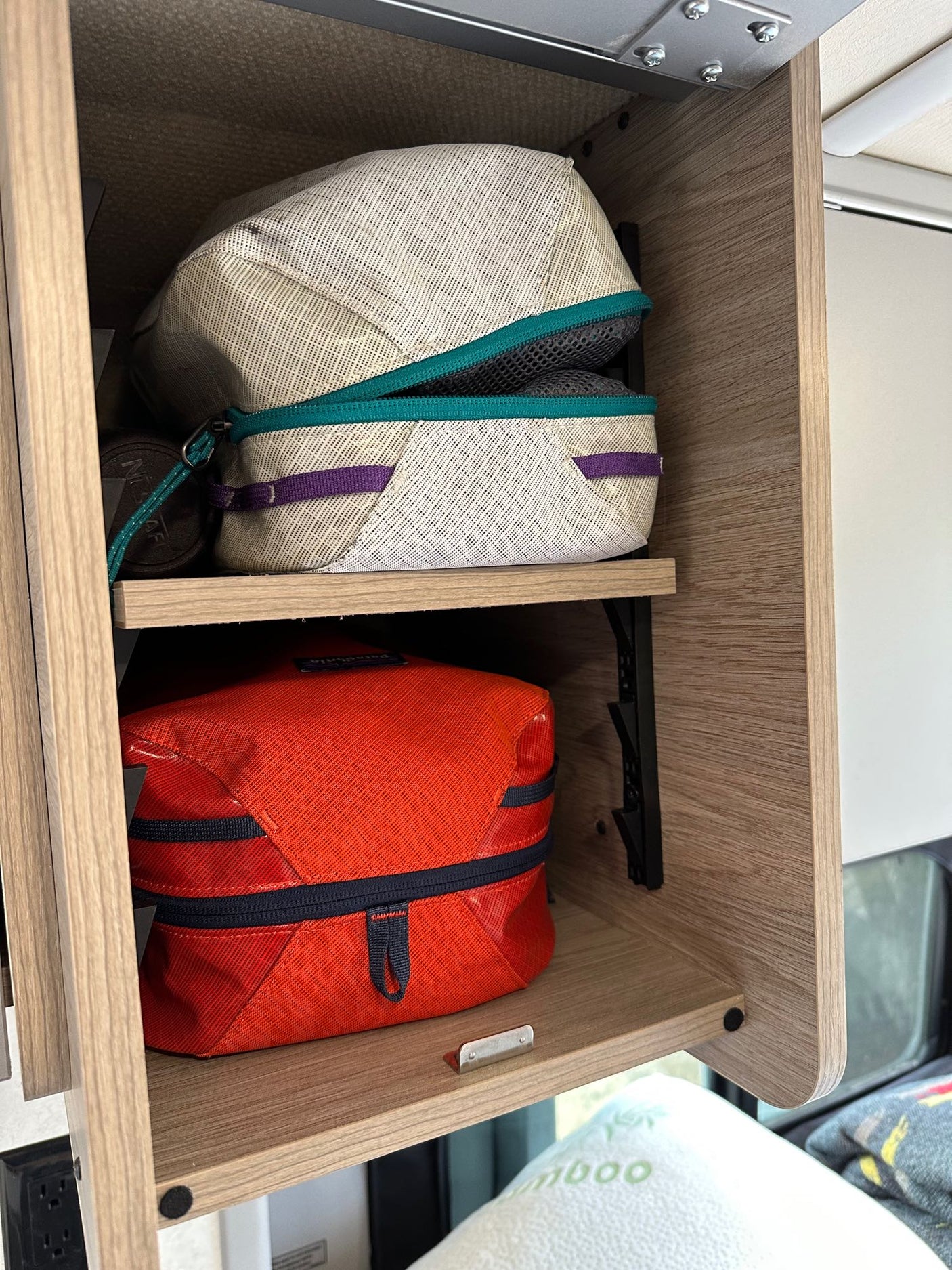 RV rental overhead cabinet shows organized packing cubes, maximizing compact storage for travel essentials.