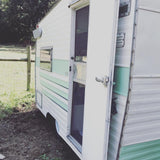 Open door of a vintage white and mint green camper/RV. Perfect for an rv rental getaway in nature.