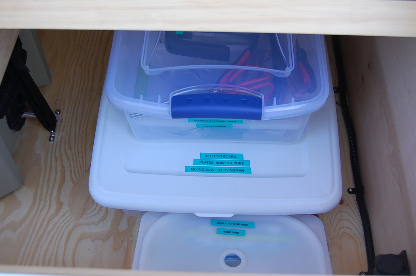 Stacked, labeled containers organize kitchen & cleaning supplies in this RV rental, maximizing space for adventure. — photo 9