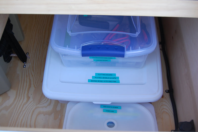 Stacked, labeled containers organize kitchen & cleaning supplies in this RV rental, maximizing space for adventure. — photo 9