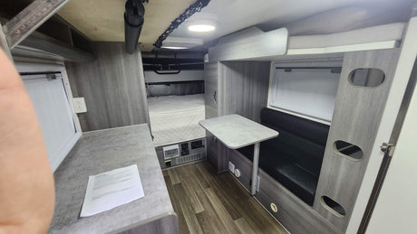 Compact RV rental interior featuring a bed, dining area, and functional living space for travel comfort.