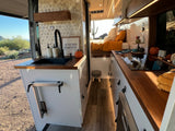Inside a cozy RV rental: kitchen, bed, and a scenic desert view. Perfect camper van living.