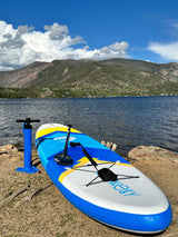 Blue inflatable paddleboard & pump at a scenic mountain lake. Perfect for RV rental outdoor trips.