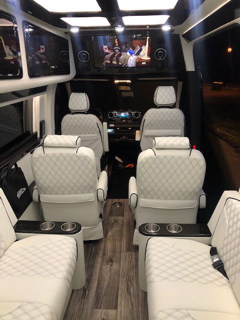 Inside a premium RV rental: luxurious white quilted seats, an entertainment screen, and elegant wood-look flooring. — photo 9