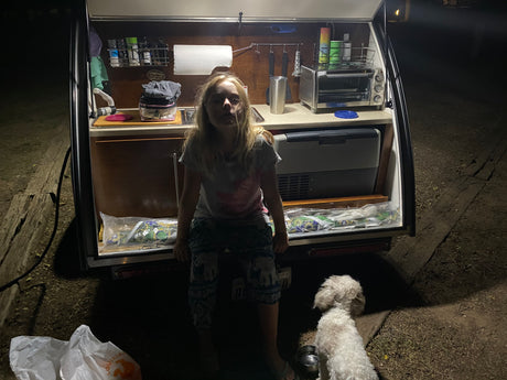 This RV rental's outdoor kitchen provides perfect camping comfort for a girl and dog at night.