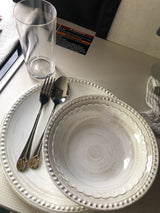 RV rental dining setup: Beaded plates, utensils, glass on a patterned counter with appliance safety warnings.
