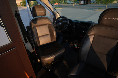Interior of this RV rental features Roadtrek branded front seats, steering wheel, and dashboard, ready for your next adventure.