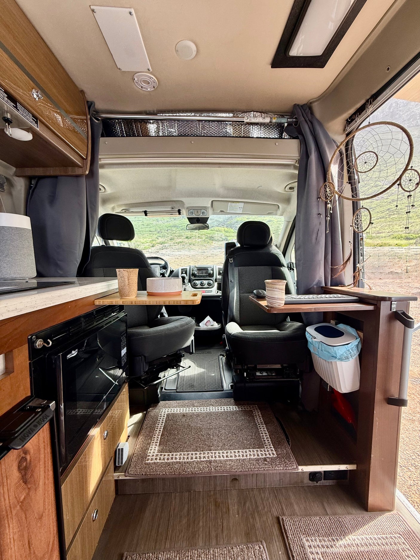 Cozy rv rental interior with a mobile workstation, compact kitchen, and swiveling front seats, perfect for a road trip.