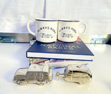Travel-themed decor: 'Always Home' mugs with car/RV graphics, a National Parks book, and silver car/RV shakers. Great for rv rental enthusiasts.