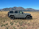 Gray Jeep Wrangler 4xe in a scenic field with mountains (likely Boulder Flatirons).