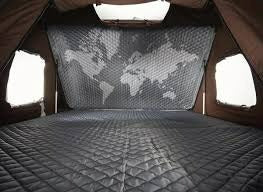 Experience comfort in an RV rental! This pop-up tent interior shows a quilted bed and a world map back panel, ideal for camping adventures.