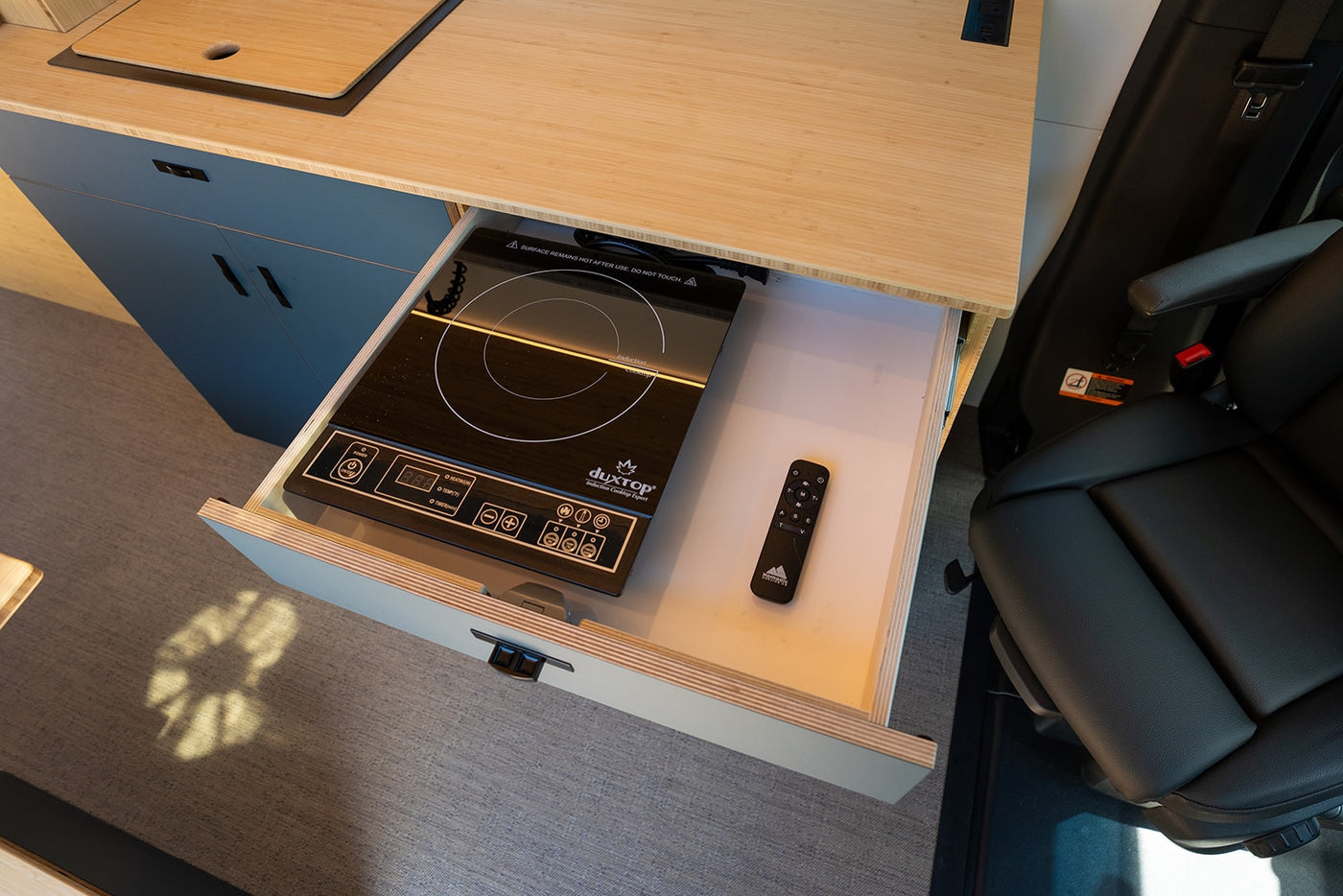 Inside an rv rental: a clever pull-out drawer reveals a Duxtop induction cooktop & remote, perfect for compact kitchen use. — photo 8