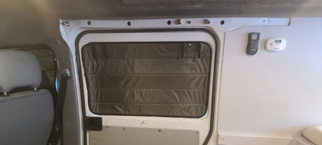 RV rental interior featuring a window with insulated cover, remote, and carbon monoxide detector for comfort and safety.