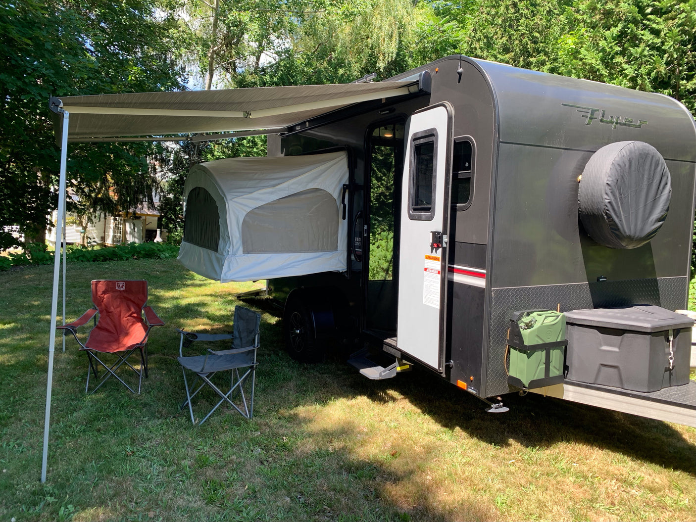 Compact rv rental trailer with pop-out tent, awning, and chairs for outdoor camping leisure. Perfect for adventure.