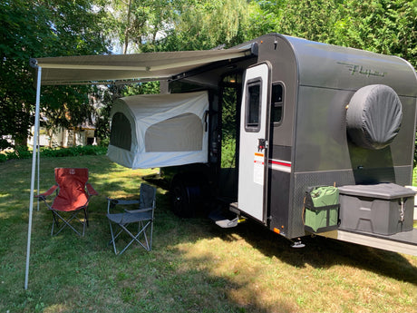 Compact rv rental trailer with pop-out tent, awning, and chairs for outdoor camping leisure. Perfect for adventure.