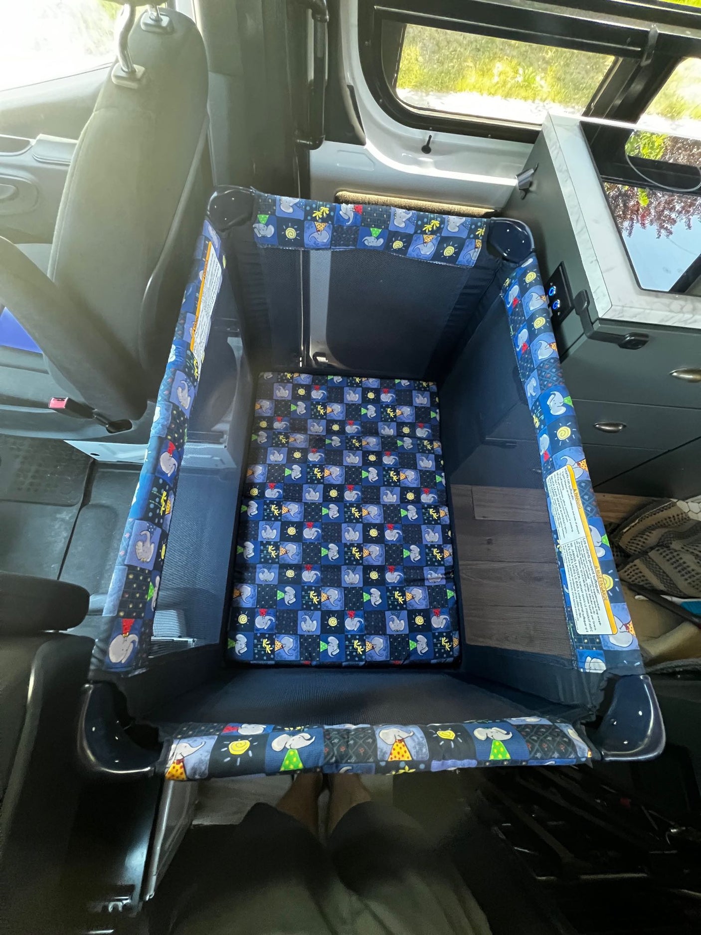 This RV rental features a portable baby playpen, creating a secure, comfortable travel sleep space for infants inside the van.