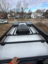 Top-down view of an RV rental van, showcasing its rooftop solar panels, AC unit, and robust roof rack system.