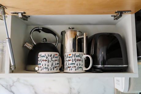 Compact RV rental kitchen cabinet. Stores kettle, French press, toaster, & mugs with RV designs. Essential amenities.