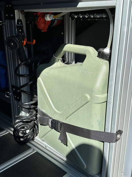 RV rental's integrated portable water and shower system. Features Reliance jug, pump, and coil hose for camping.