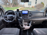 Inside a Ford Transit van, ideal for rv rental. Dashboard view with navigation, steering wheel & controls.