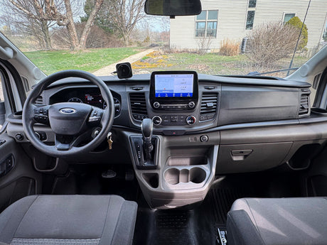 Inside a Ford Transit van, ideal for rv rental. Dashboard view with navigation, steering wheel & controls.