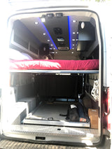 RV rental: Inside a custom camper van conversion with a comfortable sleeping area, compact kitchenette, and vibrant LED lighting.