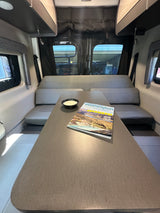Comfortable RV rental dining area with gray benches, a table, and a "Washington" travel guide, inviting adventure.