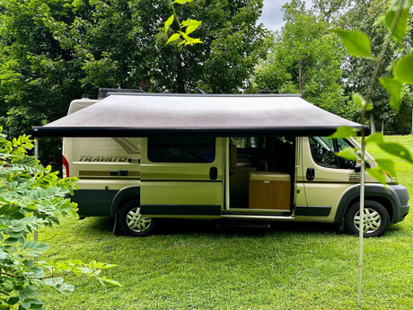  parked on grass in a wooded setting.|A modern Travato Promaster camper van