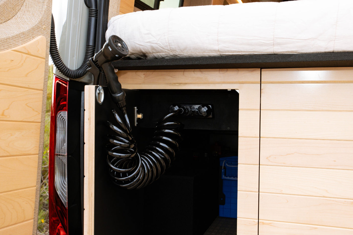 Outdoor shower and controls inside the rear storage of this RV rental.