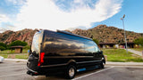 A black Mercedes Sprinter RV rental parked at a scenic mountain rest stop, reflecting clouds and sky on its shiny surface.