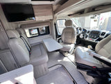 RV rental interior: light-toned seating, versatile table, TV, and driver's cockpit for comfortable travel.