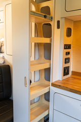 This RV rental boasts a smart pull-out pantry with multiple shelves. A convenient control panel and modern camper interior are visible.