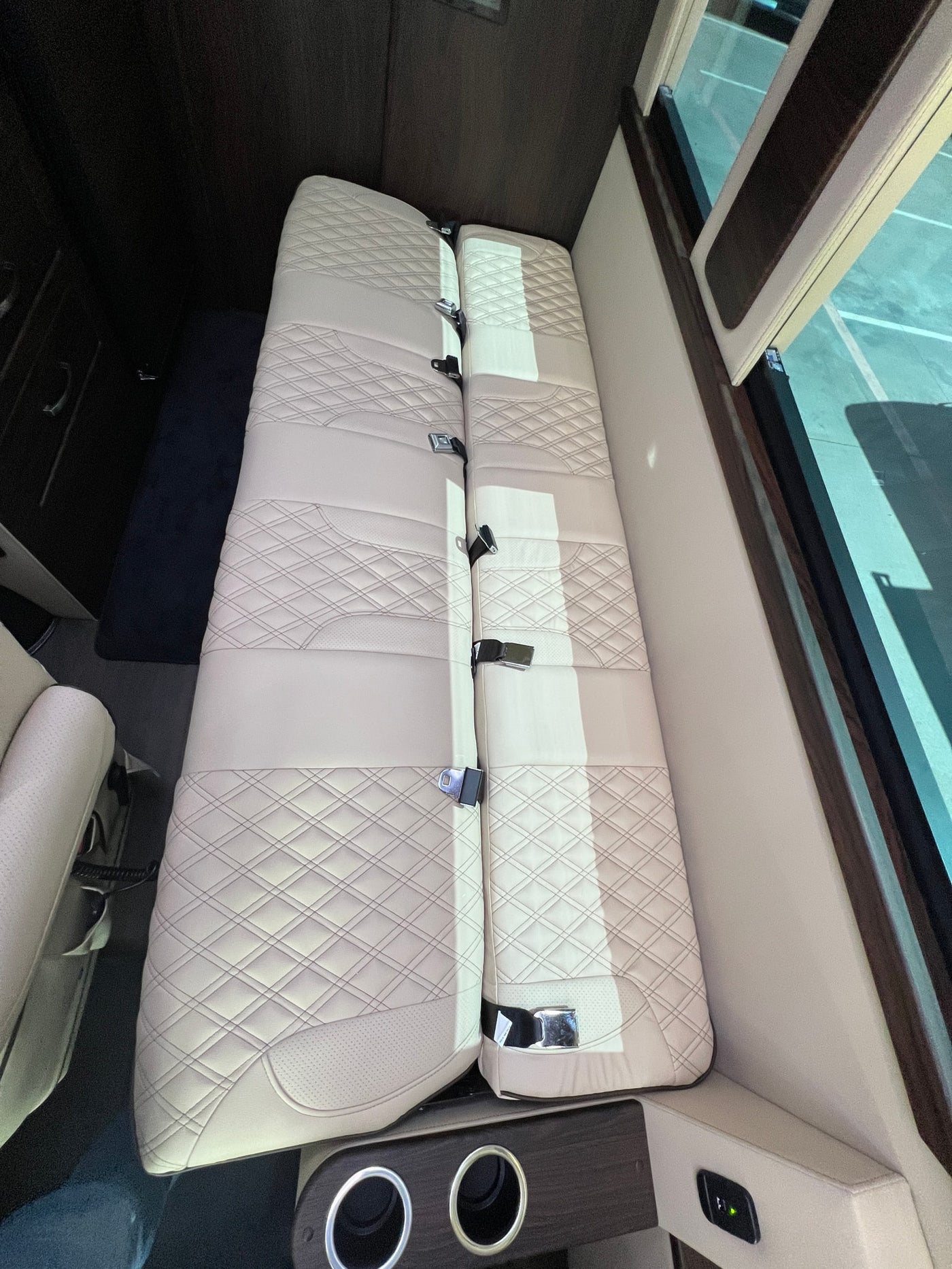 Inside an RV rental: Beige quilted seating area with seat belts and cupholders, perfect for trips. — photo 8