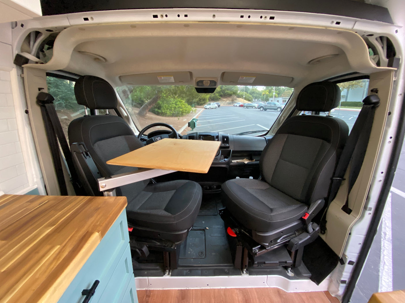 RV rental van interior showing front seats with a custom swivel table and countertop for a mobile workspace.