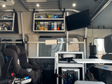 RV rental interior: custom shelves, kitchen, TV, and child car seats for family adventures.
