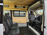 Inside an RV rental van: custom wooden interior with passenger seats, speakers, and driver's cabin access.