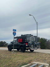Black truck with a truck camper & motorcycle on I-20 West, Texas. A versatile RV rental option for overlanding adventures.