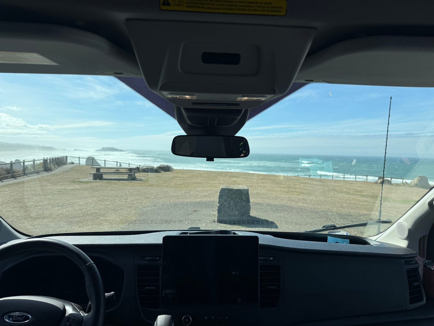 Enjoying a stunning coastal view from an RV rental, capturing ocean waves and a picnic area from inside the van. — photo 6