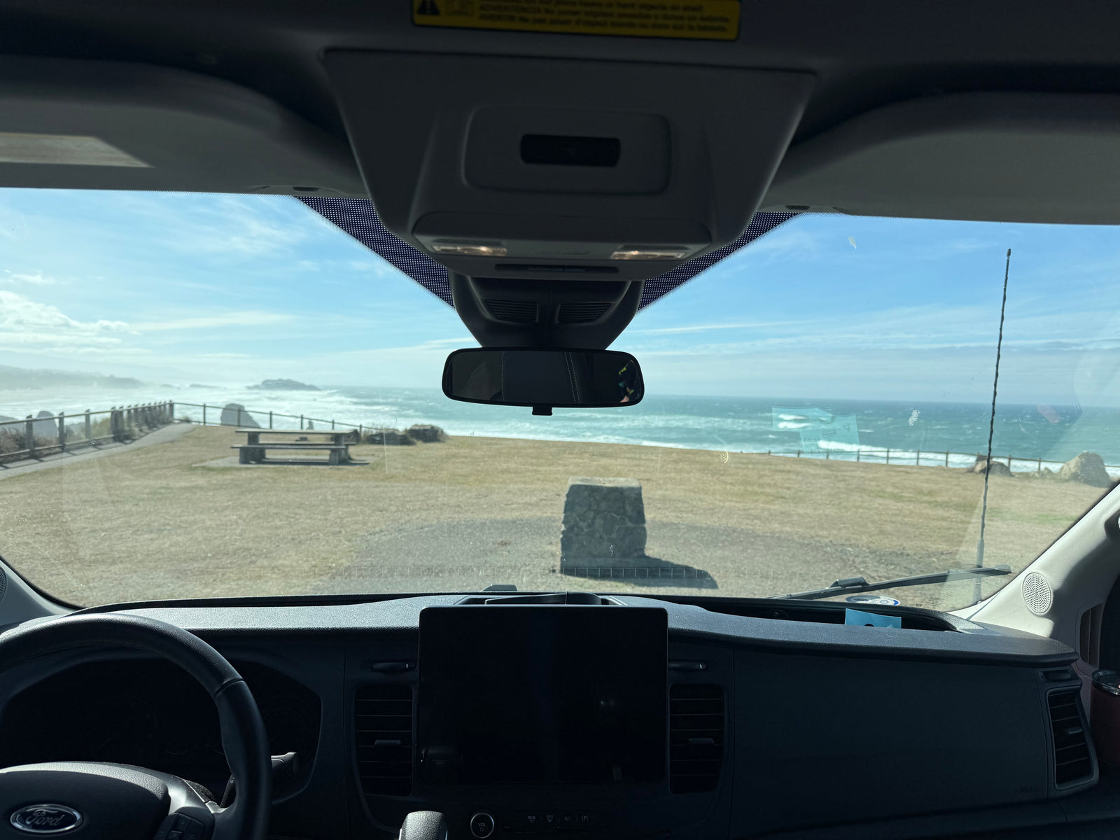 Enjoying a stunning coastal view from an RV rental, capturing ocean waves and a picnic area from inside the van.
