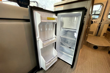 Inside an RV rental: a compact refrigerator with freezer, shelves, and door storage, ready for your next adventure's food. RV interior features.