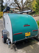 TREK teardrop camper rear view, an excellent rv rental choice. Note the roof shower, Oregon plate, and stabilizer jack.