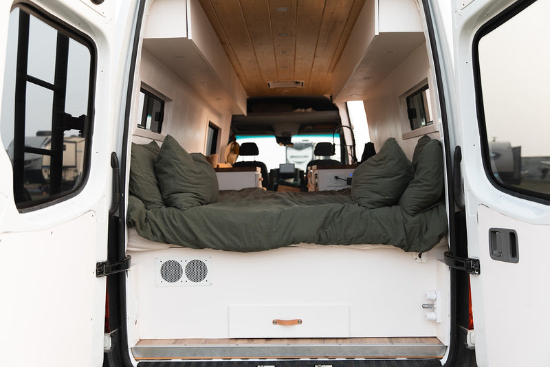  and cozy tan cushions.|Step inside this bright RV rental! Modern camper van interior with light wood & white finishes — photo 9