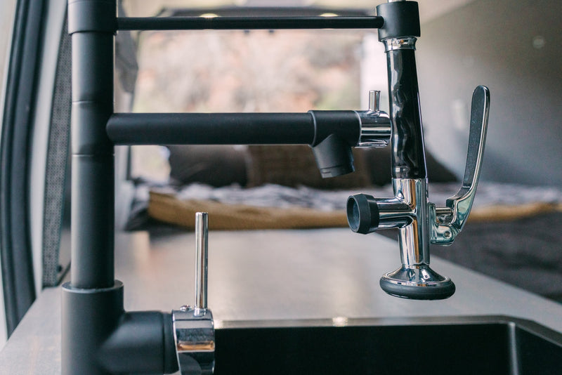 Sleek black and chrome kitchen faucet & water tap over a sink in an RV rental. Modern amenities for comfortable travels. — photo 10
