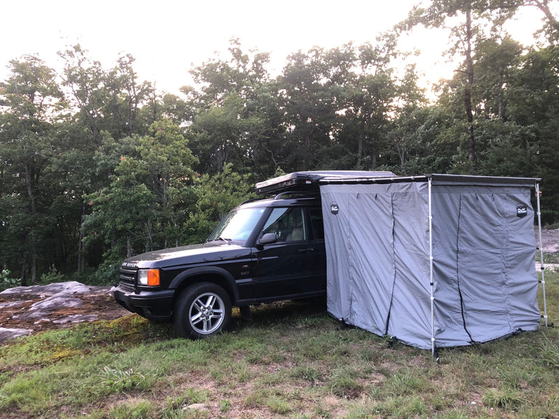  on a vibrant autumn forest trail. An adventurous RV rental option.|Black Land Rover SUV with roof-top tent and privacy awning for an RV rental style camping adventure amidst nature.|Dark SUV on an autumn forest trail — photo 8